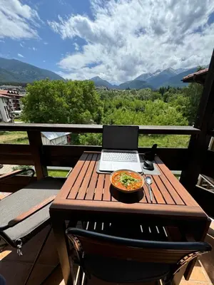 a table with a laptop and a pizza on a balcony at Modern Mountain Getaway in Bansko