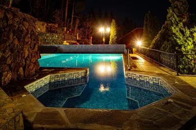 a swimming pool at night with lights at Safari Village Velingrad in Velingrad