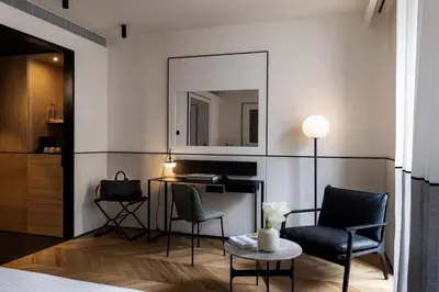 a bedroom with two chairs and a table and a mirror at Juno Hotel Sofia, a Member of Design Hotels in Sofia
