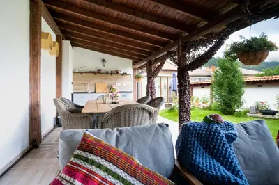 a patio with a table and chairs on a porch at Лиловата Къща in Kalofer