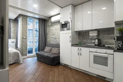 a kitchen with white cabinets and a bed in a room at Luxury Studio Silver by Flat Mаnager in Sofia