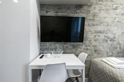 a white table with chairs and a television on a wall at Luxury Studio Silver by Flat Mаnager in Sofia