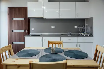 a kitchen with a table and chairs and a kitchen with white cabinets at Къща за гости Давиос in Sapareva Banya
