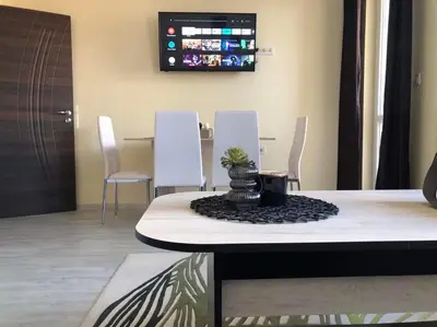 a dining room with a table and white chairs at Superb apartment Free Underground Parking in Pazardzhik
