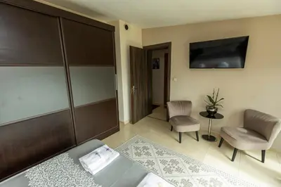a bedroom with a bed and a chair and a tv at Мезонет “Djanina” in Sandanski