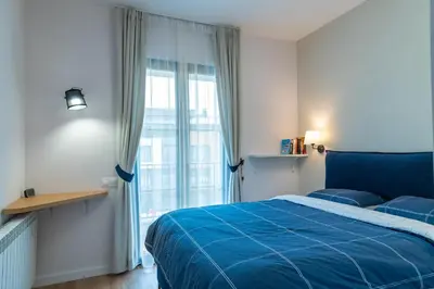 a bedroom with a blue bed and a large window at Sofia Apartment with Free Parking in Sofia