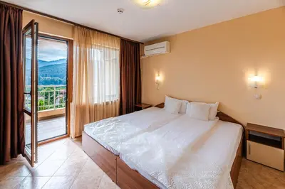 a bedroom with a large bed and a large window at ArdoVel Park Hotel in Velingrad