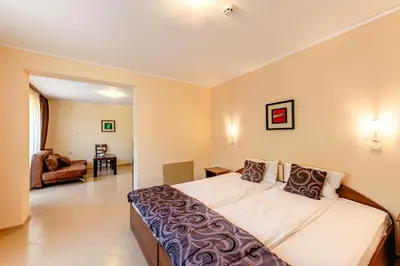 a bedroom with a large bed and a living room at ArdoVel Park Hotel in Velingrad