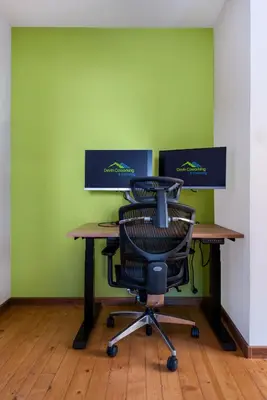 a desk with a chair in front of a green wall at DevIn Coworking & Coliving in Devin