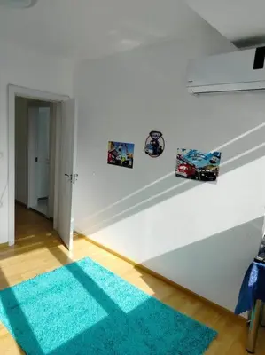 a room with a white wall and a blue rug at Alinik Apartment in Sofia