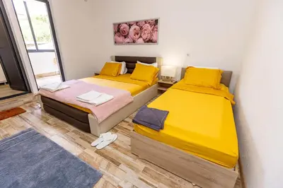 two beds in a small room with yellow sheets at APARTEMENT VIVA in Sandanski