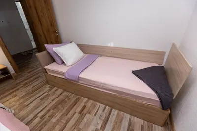 a small bed in a room with a wooden floor at Apartement Hérmitage in Sandanski