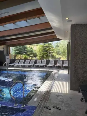 a swimming pool in a building with white chairs at St Ivan Rilski Free SPA Luxury Apartment Bansko in Bansko