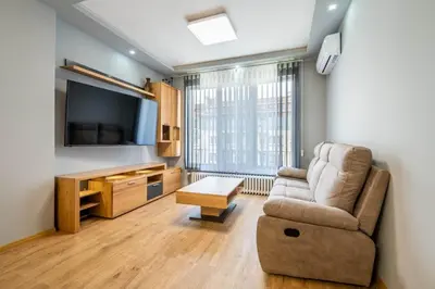 a living room with a couch and a tv at Vitoshka's Finest in Sofia