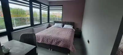 a bedroom with a bed and a table and windows at Zora in Blagoevgrad