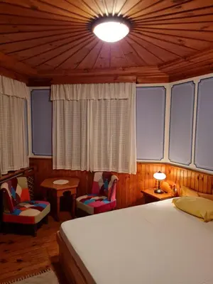 a bedroom with a bed and chairs and a ceiling at Астра къща за гости in Koprivshtitsa