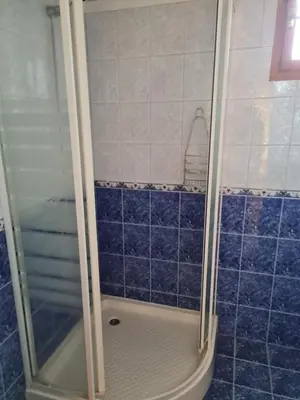 a bathroom with a shower with blue tiles at Астра къща за гости in Koprivshtitsa