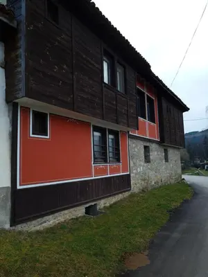 a wooden building with red accents on the side of it at Астра къща за гости in Koprivshtitsa