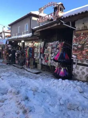 a store in a snow covered street next to a building at Lovely private apartment in Belelvedre in Bansko