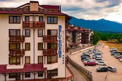 a building with a lot of cars parked in a parking lot at Lovely private apartment in Belelvedre in Bansko