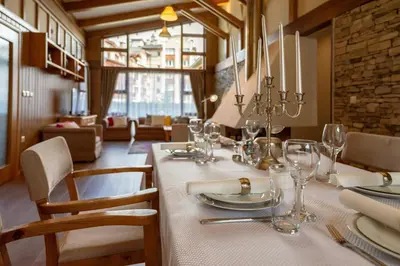 a dining room with a table with plates and glasses at Boutique Holiday Pirin Golf in Razlog