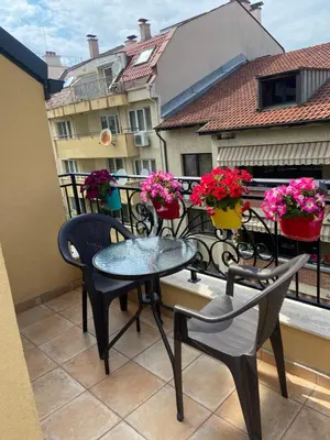 a balcony with a table and chairs and flowers at M&M Center Apartment with free parking in Plovdiv