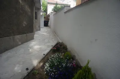 an alley with flowers next to a white wall at DaRoom in the heart of Plovdiv in Plovdiv