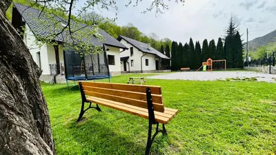 a wooden bench in a park with a playground at Тиловите къщи in Ribarica