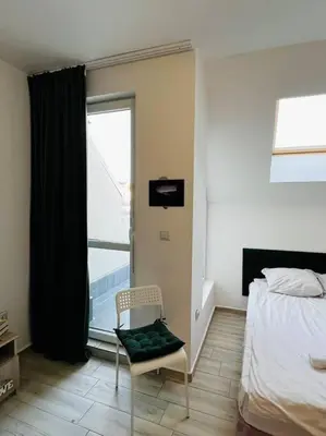 a bedroom with a bed and a chair and a window at Little Jack With Terrace in Sofia