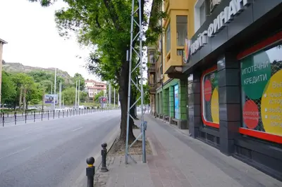an empty city street with a tree on the sidewalk at Apartment in the city center in Plovdiv